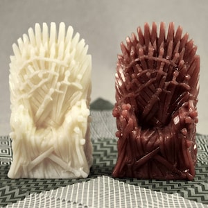 Könnte beinhalten: Zwei Miniaturversionen des Eisernen Throns aus der Fernsehserie Game of Thrones. Eine ist weiß und die andere ist braun.