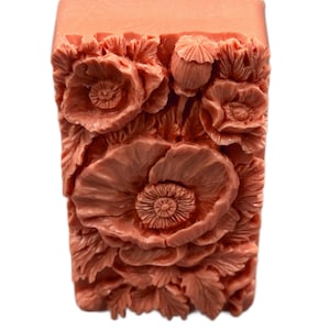 May include: A rectangular bar of soap with a floral design. The soap is a light peach color and features a raised design of poppies and leaves.