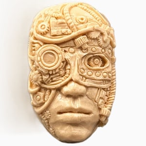 Pode incluir: Uma máscara facial esculpida bege com detalhes intrincados steampunk, incluindo engrenagens, canos e um olho grande com uma lente circular.