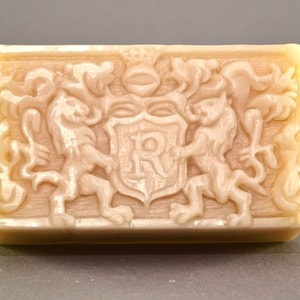 May include: A rectangular bar of soap with a detailed design of two lions flanking a shield with the letters "IR" inside. The soap is a light beige color.