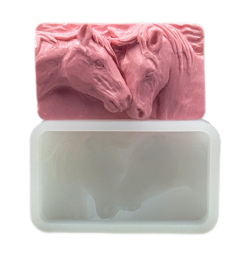 K&ouml;nnte beinhalten: Eine rosa Silikonform zum Herstellen von Seife oder Kerzen. Die Form zeigt ein detailliertes Design von zwei Pferdek&ouml;pfen, die sich die Nasen ber&uuml;hren.
