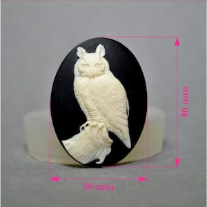 Peut inclure: Une figurine de hibou en céramique blanche sur un fond ovale noir. Le hibou est perché sur une branche et ses ailes sont déployées. La figurine mesure 7,6 cm de large et 10,2 cm de haut.