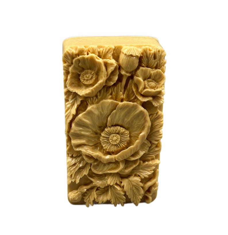 May include: A rectangular bar of soap with a detailed floral design. The soap is a light beige color and features a raised design of poppies and leaves.
