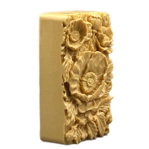 May include: A rectangular bar of soap with a detailed floral design. The soap is a light beige color and features a raised design of poppies and leaves.