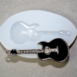 Könnte beinhalten: Ein schwarzer und silberner Gitarrenanhänger mit einer silbernen Schlaufe zum Anbringen an einer Halskette oder einem Armband. Der Anhänger ist neben einer Silikonform einer Gitarre abgebildet.