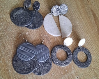May include: A set of six silver and black earrings with various shapes and textures. The earrings are made of polymer clay and have a modern, minimalist design.