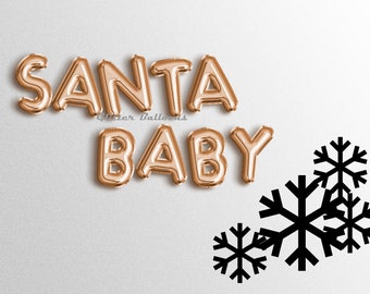 May include: Gold foil letter balloons spelling "SANTA BABY" with black snowflake cutouts on a white background.