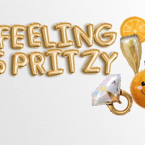May include: Gold foil balloons spelling "Feeling Spritzy" with a gold champagne flute, a gold ring with a diamond, and a gold orange balloon with a smiley face.
