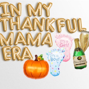 Puede incluir: Globos de letras de lámina dorada que deletrean "IN MY THANKFUL MAMA ERA" con un globo de calabaza, un globo de botella de champán y dos globos de huella de bebé que dicen "It's a Boy!" e "It's a Girl!"