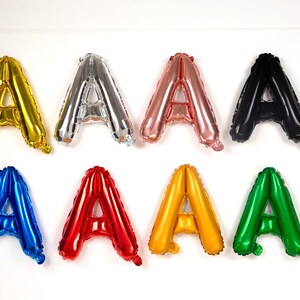 May include: Eight foil balloons shaped like the letter "A" in various colors: gold, silver, rose gold, black, blue, red, yellow, and green. These balloons are suitable for party decorations.