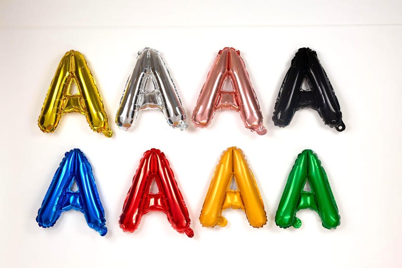 May include: Eight foil balloons shaped like the letter "A" in various colors: gold, silver, rose gold, black, blue, red, yellow, and green. These balloons are suitable for party decorations.