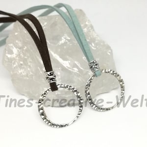 May include: Two silver textured circle pendants on brown and light blue suede cords.