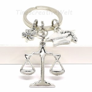 May include: Silver keyring with a graduation cap, a four-leaf clover charm, and a scale of justice charm.