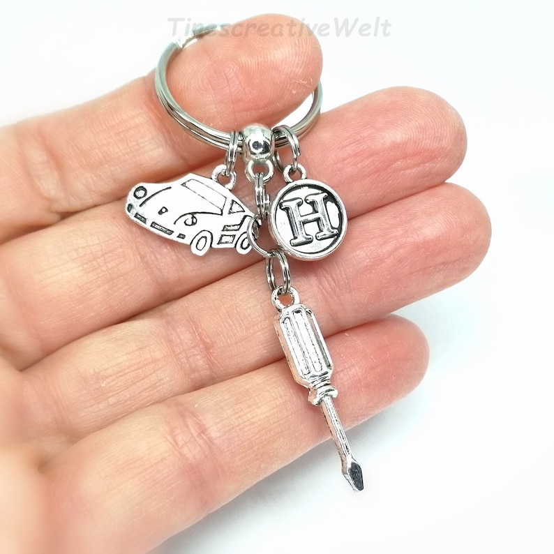 K&ouml;nnte beinhalten: Silberner Schl&uuml;sselanh&auml;nger mit einem Auto-Anh&auml;nger, einem Schraubendreher-Anh&auml;nger und einem Anh&auml;nger mit dem Buchstaben H.