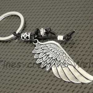 May include: Silver key chain with a detailed silver wing charm and black leather cord.