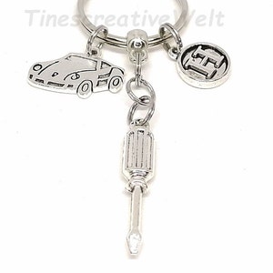 K&ouml;nnte beinhalten: Silberner Schl&uuml;sselanh&auml;nger mit einem Auto, einem Schraubendreher und einem Anh&auml;nger mit dem Buchstaben H.
