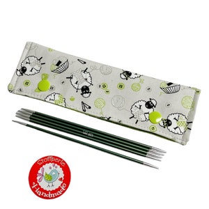 Könnte beinhalten: Ein Set mit sechs grünen Stricknadeln in einer Stoffhülle mit Schaf-Motiv. Die Hülle hat einen grünen Knopf und den Text "Stoffperle Handmade".