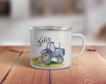 May include: White enamel mug with a blue tractor and hay bales design. The mug has the name "Felix" written on it.