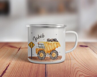 May include: White enamel mug with a yellow dump truck carrying rocks, a yellow road sign with two arrows pointing up, and the name "Jakob" printed on the side.