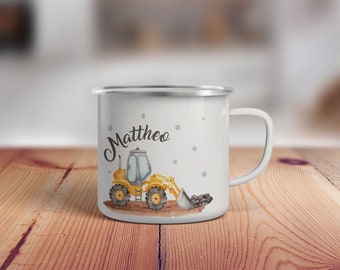 May include: White enamel mug with a yellow construction vehicle and the name "Mattheo" in black lettering.