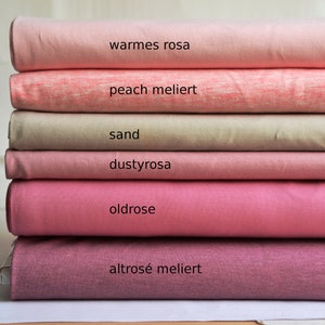 K&ouml;nnte beinhalten: Ein Stapel aus sechs gefalteten Stoffballen in verschiedenen Rosa-, Pfirsich- und Sandt&ouml;nen. Die Stofflagen sind mit folgendem Text beschriftet: warmes rosa, peach meliert, sand, dustyrosa, oldrose und altros&eacute; meliert, was die Farbe angibt.