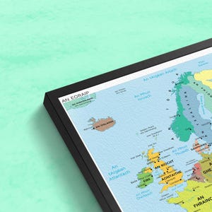 Pu&ograve; includere: Una mappa colorata dell'Europa con i nomi dei paesi in gaelico irlandese. La mappa &egrave; incorniciata in nero e ha uno sfondo blu chiaro. La mappa include l'Islanda, la Groenlandia e le Isole britanniche.