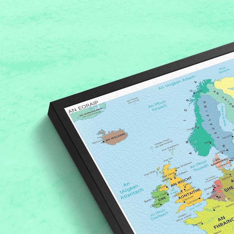 Pu&ograve; includere: Una mappa colorata dell'Europa con i nomi dei paesi in gaelico irlandese. La mappa &egrave; incorniciata in nero e ha uno sfondo blu chiaro. La mappa include l'Islanda, la Groenlandia e le Isole britanniche.