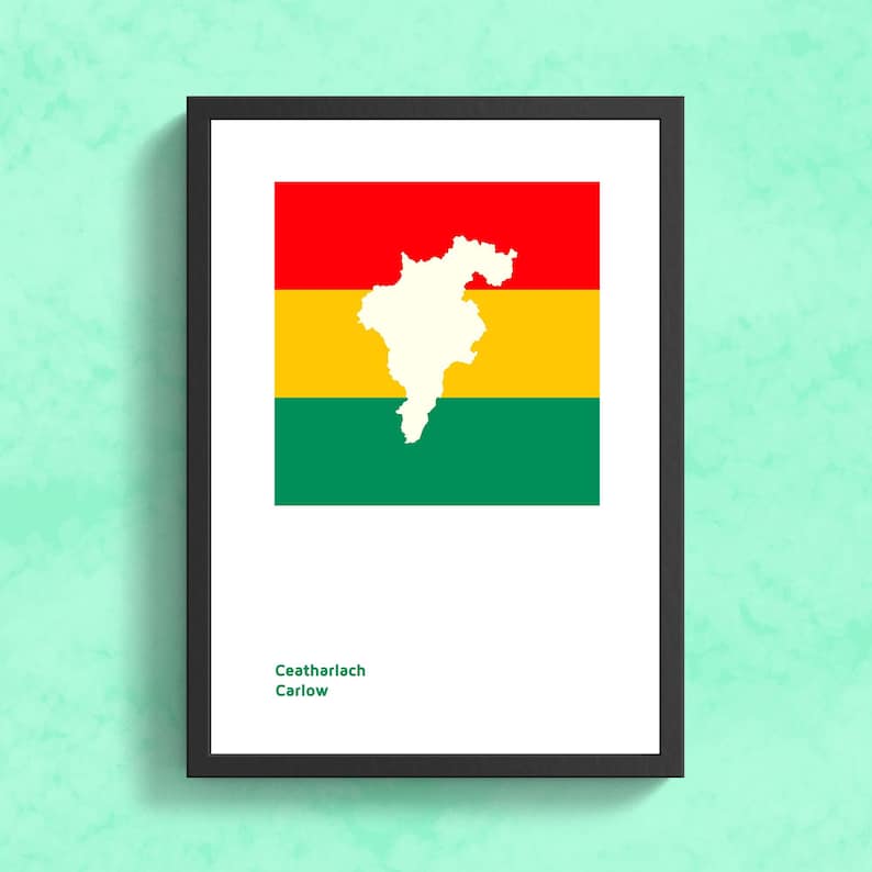 May include: A framed print of the flag of Carlow, Ireland. The flag is red, yellow, and green with a white outline of the county of Carlow in the center. The text "Ceatharlach Carlow" is printed below the flag.