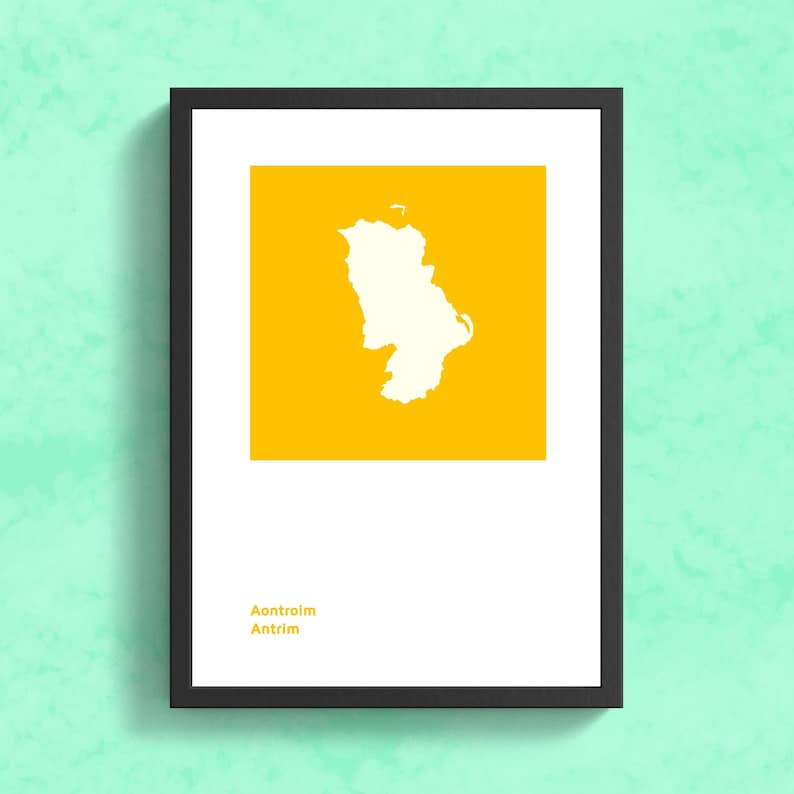 Puede incluir: Impresi&oacute;n art&iacute;stica enmarcada con un contorno blanco de una regi&oacute;n geogr&aacute;fica sobre un fondo amarillo. La impresi&oacute;n incluye el texto "Aontroim Antrim" en la parte inferior, todo dentro de un marco negro. La obra de arte se muestra contra una pared texturizada verde claro.