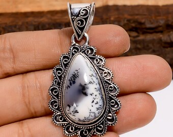 Pode incluir: Pingente de prata com uma pedra branca e cinza em forma de gota. A pedra é engastada em uma moldura decorativa em estilo filigrana. O pingente tem uma argola para prender a uma corrente.