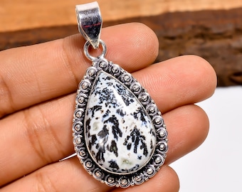 May include: A teardrop-shaped pendant with a white and black patterned stone set in a silver-colored metal frame. The frame has a beaded border and a loop for a chain.