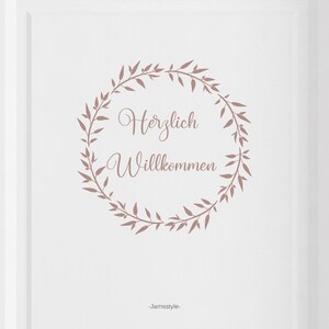 May include: A white background with a brown floral wreath that says "Herzlich Willkommen" in the centre. The text is in a cursive font. The bottom of the image says "Jamstyle".