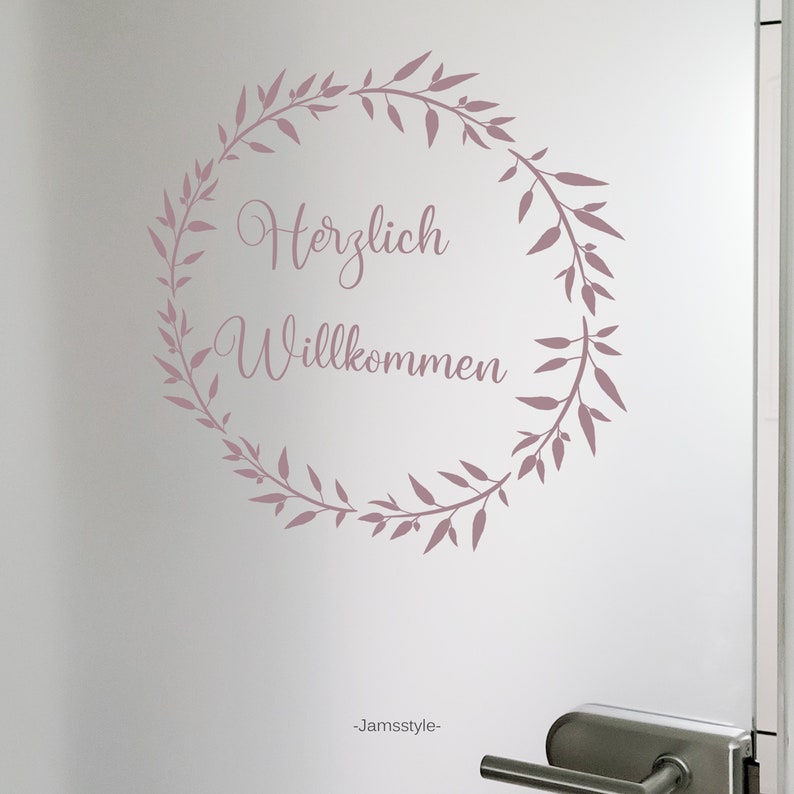 May include: A pink floral wreath with the text "Herzlich Willkommen" in a cursive font.