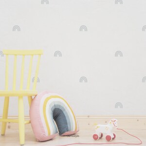 Puede incluir: Una silla de madera amarilla con una almohada de colores arco&iacute;ris delante. La pared detr&aacute;s de la silla est&aacute; decorada con calcoman&iacute;as de arco&iacute;ris grises.