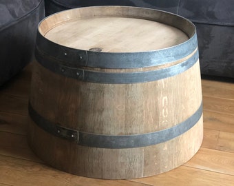 Könnte beinhalten: Ein runder Couchtisch aus Holz in Form eines Fasses mit zwei Metallbändern um die Ober- und Unterseite. Der Tisch steht auf einem Holzboden.