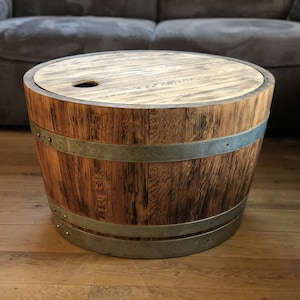 May include: A round wooden table made from a repurposed barrel with a metal band and a wooden top. The table has a small hole in the top.