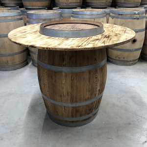 May include: A wooden barrel table with a round top and a metal band around the top. The table is made from reclaimed wood and has a rustic look.
