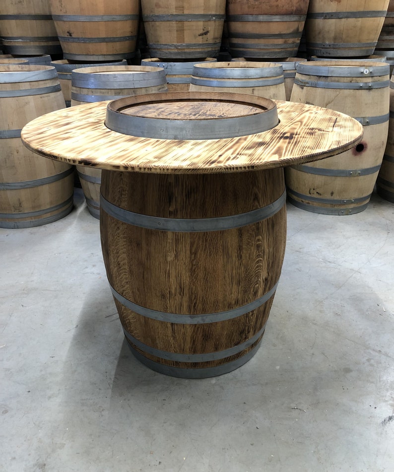 May include: A wooden barrel table with a round top and a metal band around the top. The table is made from reclaimed wood and has a rustic look.