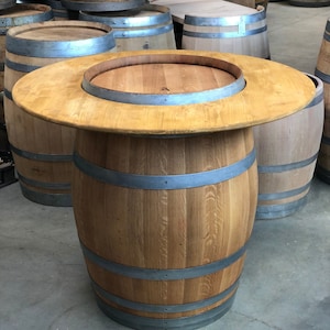 May include: A wooden barrel table with a round top and metal bands. The table is made from a single barrel and has a natural wood finish.