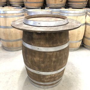May include: A wooden barrel table with a brown stain and silver metal bands. The table top is made of wood and has a round shape.