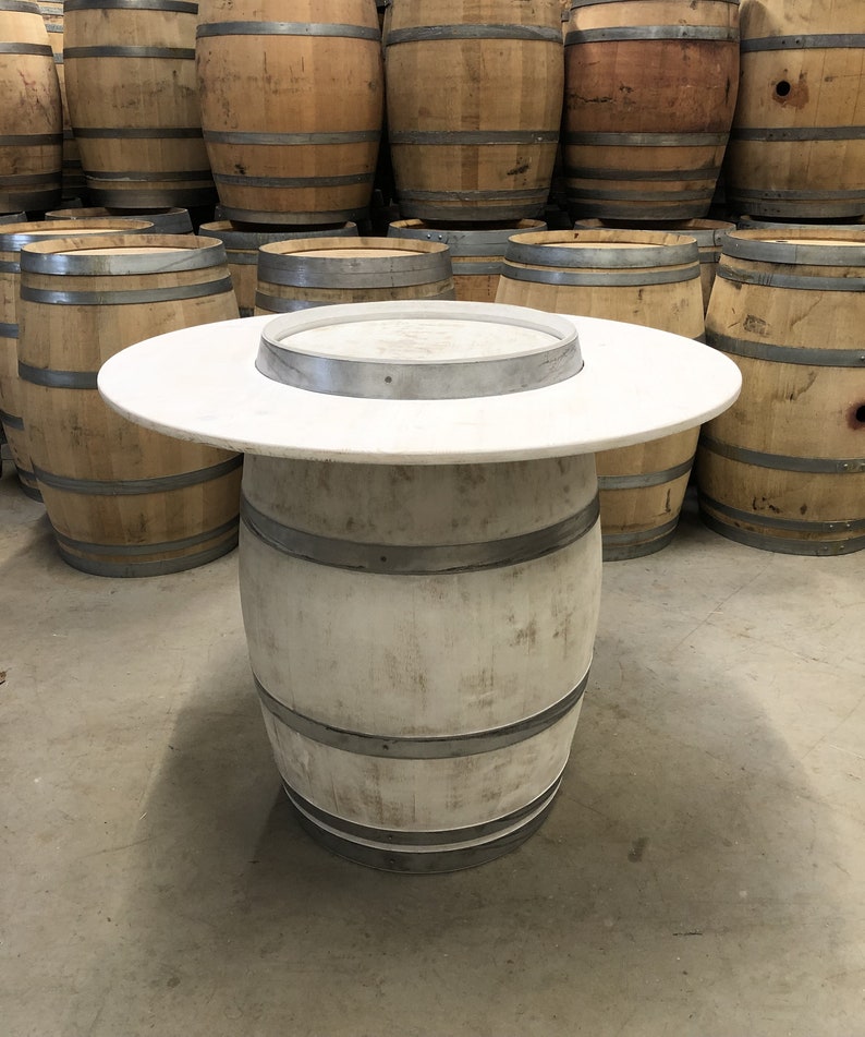 May include: White painted wooden barrel with a white round tabletop. The barrel is used as a table and has metal bands around it.