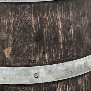 May include: A dark brown wooden barrel with two silver metal bands and rivets. The barrel has a rustic, weathered look.