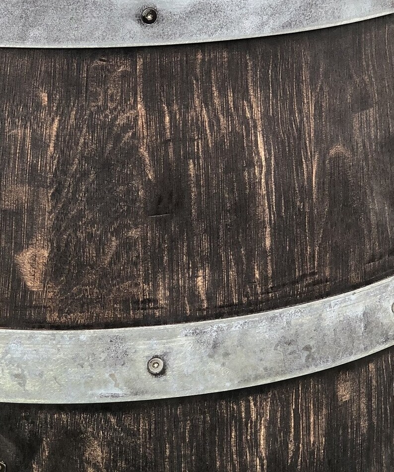 May include: A dark brown wooden barrel with two silver metal bands and rivets. The barrel has a rustic, weathered look.