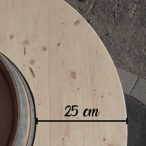 May include: A close-up of a light wood round tabletop with a dark grey ring in the centre. The tabletop measures 25 cm in diameter.