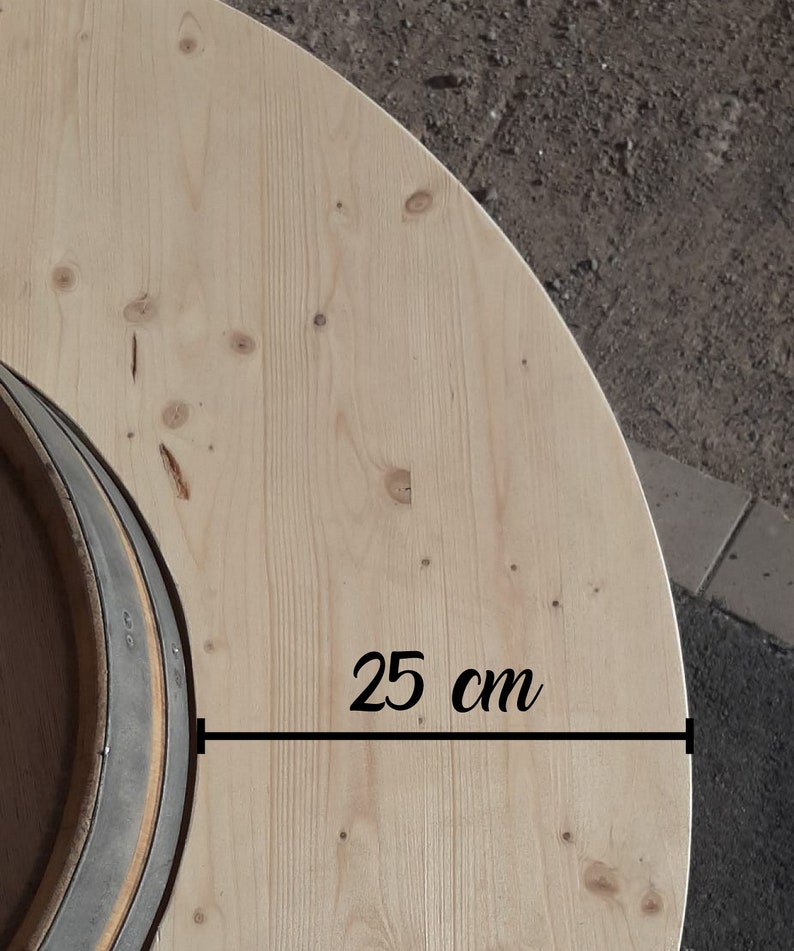 May include: A close-up of a light wood round tabletop with a dark grey ring in the centre. The tabletop measures 25 cm in diameter.