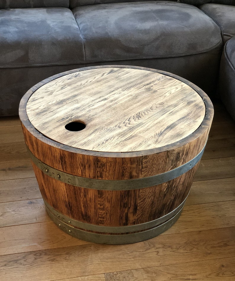 May include: A round wooden table made from a repurposed barrel with metal bands. The table has a wooden top with a small hole in the center.