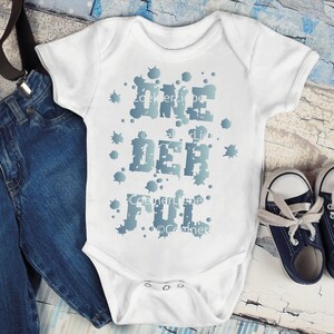 Könnte beinhalten: Weißer Baby-Strampler mit einem blauen und weißen Spritzmuster und dem Text "One Der Ful" in fetter Schrift.