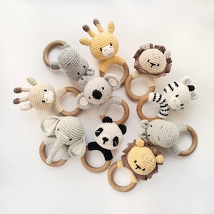 May include: A set of nine crocheted animal teethers with wooden rings. The animals include a giraffe, lion, zebra, panda, elephant, koala, and two hippos. The teethers are in shades of gray, black, white, and yellow.