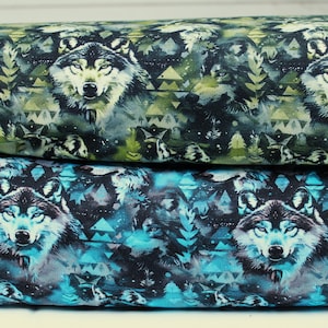 Könnte beinhalten: Zwei Stoffrollen mit Wolfsmotiven. Die obere Rolle zeigt ein grünes und schwarzes Muster mit Wolfsgesichtern, Bäumen und geometrischen Formen. Die untere Rolle hat ein blaues und schwarzes Muster mit Wolfsgesichtern und geometrischen Formen.