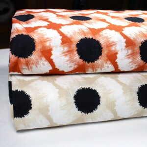 Könnte beinhalten: Zwei Stoffstücke mit weißem Hintergrund und schwarzen und orangefarbenen Blumenmustern. Das obere Stoffstück ist orange mit schwarzen Blumen. Das untere Stoffstück ist beige mit schwarzen Blumen.